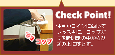 注目がコインに向いているスキに、コップだけを新聞紙の中からひざの上に落とす。